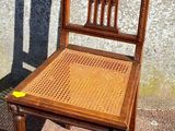 une chaise en bois posée contre un mur sur le trottoir