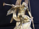 bronze statue of a woman sitting on a rock with a bow and arrow