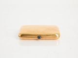 an image of a gold cigarette case with a blue stone