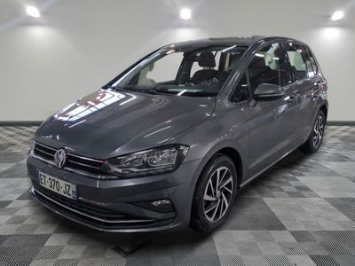 La Volkswagen Touran est garée dans une grande pièce au sol carrelé en damier.