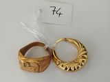 two gold rings on a white surface with a price tag