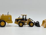 three toy construction vehicles sitting next to each other on a white surface