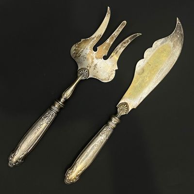 paire d'ustensiles de service anciens en métal argenté sur fond noir