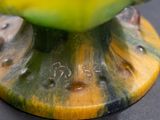 a close up of a yellow and green vase on a table