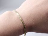 a gold chain bracelet on a woman ' s arm