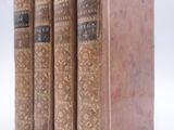 three old books sitting on top of each other on a white surface