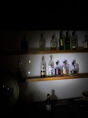 de nombreuses bouteilles d'alcool posées sur une étagère dans l'obscurité