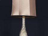 lampe de table en verre doré avec un abat-jour rose posée sur un socle noir