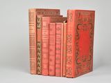 trois livres rouges superposés sur une surface blanche