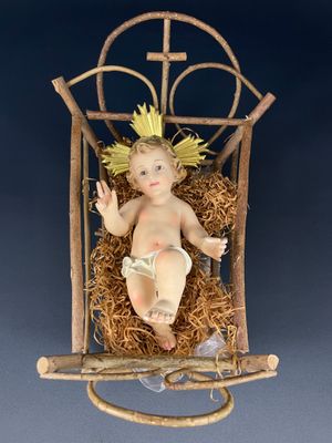 figurine représentant l'Enfant Jésus dans une crèche surmontée d'une croix