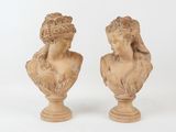 pair of carved busts of women on pedestals against a white background