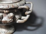 a silver vase with a handle on a table