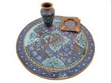 une assiette bleue sur laquelle est posé un vase, posée sur une surface blanche