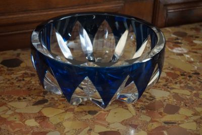 un saladier en verre bleu contenant des cuillères, posé sur une table