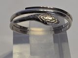 une bague en argent ornée d'un serpent, posée sur une surface transparente
