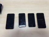 four cell phones are sitting on a table with one broken screen