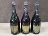 trois bouteilles de vin posées sur une table l'une à côté de l'autre