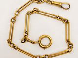 a close up of a gold chain with a ring on it