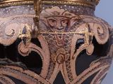 a black vase with a gold decoration on it