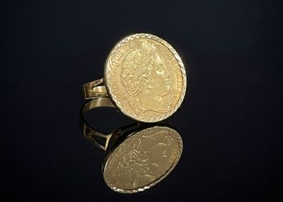 une image représentant une bague avec une pièce d'or posée sur une surface noire