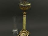 une image représentant une lampe de couleur dorée, dotée d'un abat-jour en verre, posée sur une table
