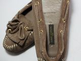 une paire de mocassins marron posés sur une surface blanche, sur fond blanc