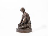 statue en bronze représentant une femme assise sur un rocher, sur fond blanc