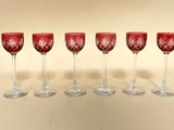 six verres à vin rouge alignés en rang sur une table