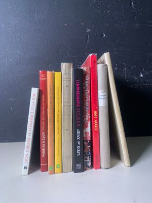 une pile de livres posée sur une table près d'un mur noir