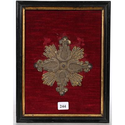 une photo encadrée représentant une croix en or sur un fond de velours rouge
