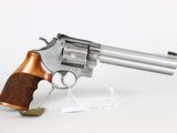 a close up of a revolver with a wooden handle on a white surface