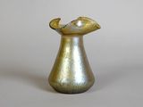 a gold vase with a curved handle on a white surface