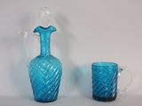un pichet en verre bleu et un verre posés sur une table
