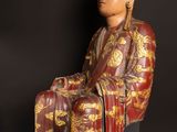 an image of a wooden statue of a man sitting on a chair