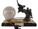 a lamp that is sitting on a book with a bird figurine next to it