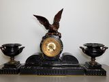 a clock with an eagle on top of it next to two vases