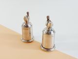 pair of silver pepper shakers sitting on top of a yellow and white surface
