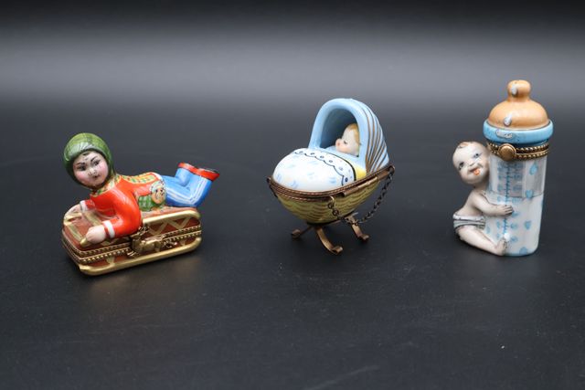 Trois boîtes en porcelaine : berceau avec enfant, enfant avec bib...