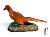 une figurine représentant un faisan perché sur un rocher