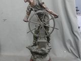 bronze statue of a man on a ship steering a wheel