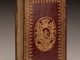 an old book with a gold and red cover sitting on top of a table