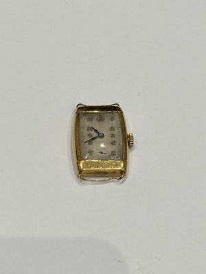 a small gold watch sitting on a white surface