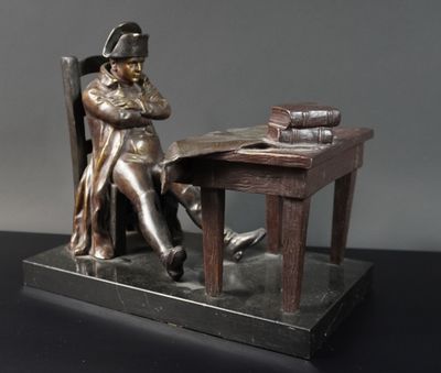 une statue représentant un homme assis à un bureau, un livre à la main