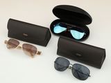 three pairs of sunglasses and a case on a white surface