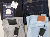 three pairs of men ' s jeans and a cell phone sitting on a table