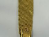 a close up of a gold bracelet on a white surface