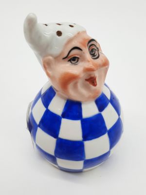 une petite figurine en céramique bleue et blanche représentant un clown