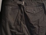 black pants hanging on a hanger in front of a white wall