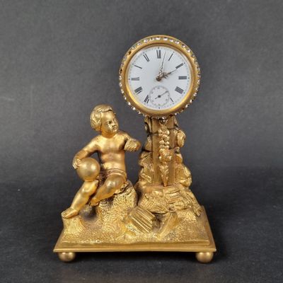 a gold clock sitting on top of a table next to a figurine