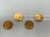 un groupe de quatre pièces d'or posées sur une surface blanche